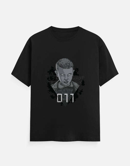 “Black t-shirt featuring a grayscale portrait of Eleven with '011' text and the alphabet wall from Stranger Things in the background.”